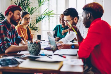 Hometask üzerinde birlikte çalışma akıllı kadın ve erkek öğrencilerin yaratıcı fikirler, tablo toplantı ile her diğer iletişim oturumları beyin fırtınası sırasında oturan çalışanların çok ırklı mürettebat paylaşmak.