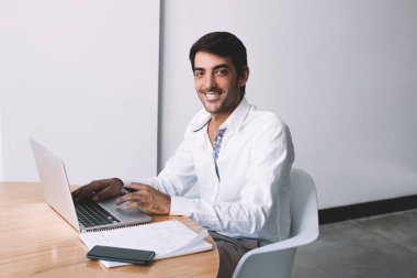 Dizüstü bilgisayar şirket ofisinde, pozitif işadamı masaüstü ile kağıtları ve netbook arama bilgi çalışanı ile verimli toplantı için çalışan erkek yönetmen vakit gülümseyen