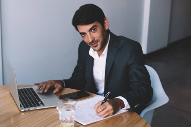 Şirket yolu ile dizüstü bilgisayar aygıt için logo oluşturma ve ders kitabı, başarılı bir adam iş için modern netbook kullanarak office wifi bağlı fikirler yazma gülümseyen erkek grafik tasarımcı portresi