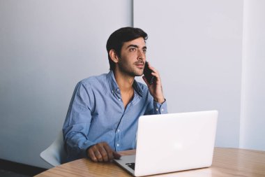 Ciddi erkek bu masada oturan ve denge kontrol ve dizüstü bilgisayar, netbook ve telefon iletişim için kullanan profesyonel adam üzerinden işlem yapmak için müşteri hizmetleri çağrı geliştirici