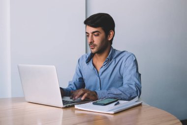 Yakışıklı ciddi erkek programcı klavye kodu dizüstü cihaz üzerinde verimli çalışması için Wi-Fi bağlantısı kullanarak web sayfası oluşturmak için resmi konsantre erkekte giymek izlerken webinar netbook üzerinde