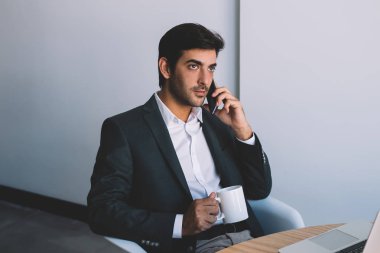 Yakışıklı ofis çalışanı operatör bağlantı sırasında kahve molası, formal giyim kafein içecek kapalı fincan zevk meslektaşı ile konuşurken genç adam kullanarak uygulama üzerinden cep arama yapma