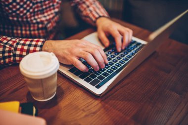 Erkek eller için ücretsiz kablosuz internet kafede, bu modern netbook ile uzaktan çalışma profesyonel bağlı dizüstü bilgisayarda klavye üzerinden Web sitesi için bilgi girmeye resim kırpılmış