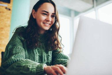 Gülümseyen yetenekli kadın freelancer uzaktan ağ dizüstü bilgisayarı üzerinde çalışarak başarılı online iş ile neşeli esmer hippi kız arkadaşımdan dizüstü bilgisayarda sohbet mesajı almak için mutlu memnun.
