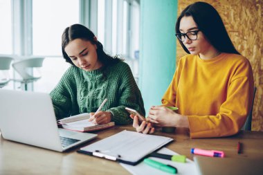 Araştırma ve planlama, ciddi erkek arkadaşı defter vasıl okul sırası ofiste oturan yazma sırasında cep mesaj gönderme için teknolojisini kullanarak işlem dalgın kadın konsantre