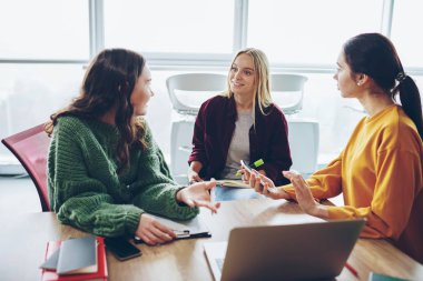 Kadın tasarımcılar konuşmayı ofis, dizüstü bilgisayar yanında strateji oturma planlama onun meslektaşım için fikirler açıklayan genç kadın coworking içinde işbirliği süreci sırasında pozitif mürettebatı