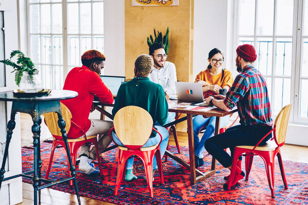 Cheerful male and female members of working team satisfied with  cooperation process share creative ideas during discussion,multiracial colleagues having fun during workshop with professional coac