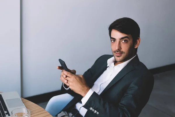 英俊男子肖像坐在商务房里手持智能手机设备 看着相机 印度雇主使用正式服装中的蜂窝磨损现代办公室连接到无线互联网 — 图库照片