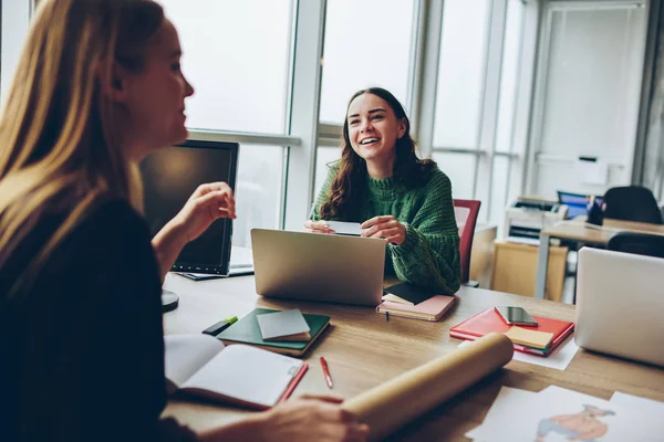 微笑的年轻妇女在办公室的桌面合作中玩得开心 快乐的女同事用现代技术共同项目协作 在工作过程中笑笑话 — 图库照片