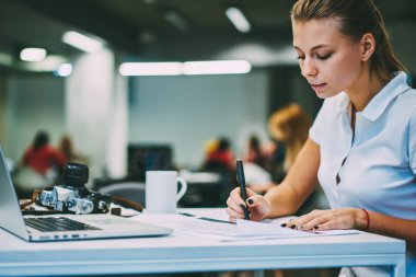 Dalgın akıllı hipster öğrenci yazma eğitimi üniversitede modern dizüstü bilgisayar ile masada oturma sınayın. Genç kadın notlar tabii yaklaşan sınavlar için hazırlanıyor işe konsantre