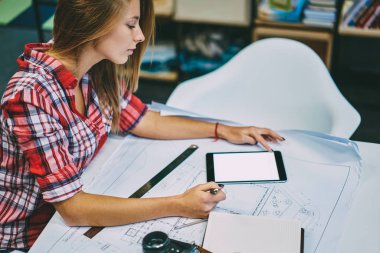 Genç kadın çalışması eskiz bina sırasında online eğitsel modern dokunmatik yüzey izlerken yan görünüm kırpılmış. Bilgi web sitesinde dijital tablet kopya alanı ile arama yetenekli kadın mimar