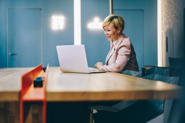 Olgun bir koç, internetten internete bağlı internet üzerinden iş sitelerini izlerken gülüyor. 50 yaşındaki neşeli bayan girişimci netbook 'tan komik haberler okuyor.