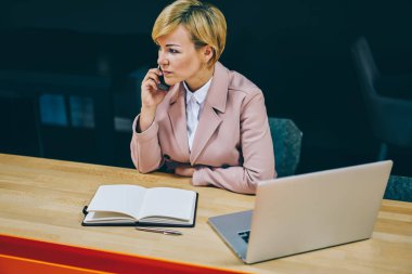 Kadın koç 50 yaşında modern Dizüstü aygıtı Üniversitesi'nde oturan smartphone aygıt arama deneyimli. Olgun işkadını bilgisayarda kablosuz internet ile hücresel çalışma hakkında konuşmak