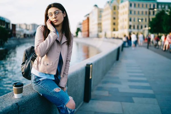 严重的年轻女子穿着时髦的衣服 在镇上的河岸上休息 在度假的漫游电话 时髦的女孩等待男朋友在城市设置手机通话 — 图库照片