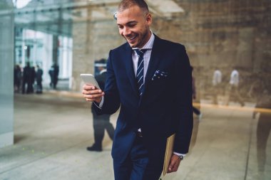 Pozitif başarılı Finans Müdürü Smartphone cep telefonu ile komik Haberler ile gelen bildirim okurken gülmekten formal giyim giymiş. Neşeli işadamı cep sms iyi haber alınıp