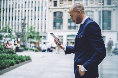 Dalgın emin işadamı smartphone aygıt ayakta kentsel ortamda gelen bildirim okuma formal giyim giymiş. 4 g internet bağlantısı kullanarak telefon app güncelleme girişimci