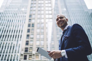 Formal giyim uzağa 4 g internet yüksek gökdelenler ile modern şehir merkezinde yürüyüş kullanarak dijital tablet uygulaması yüklenirken seyir aşağıda mutlu başarılı girişimci görünümü giymiş
