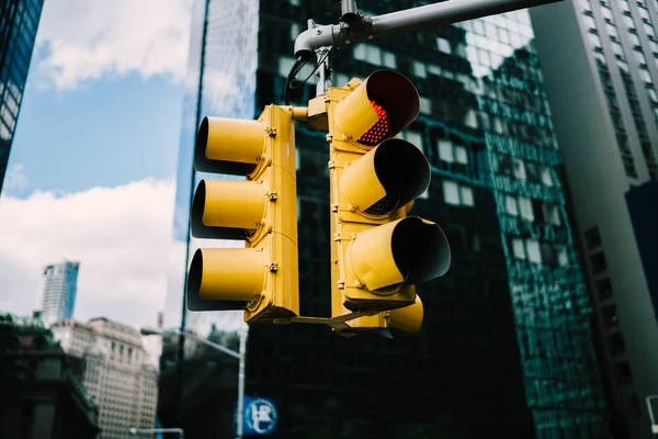 Equipment for transport controlling light up lamps with colours signs hanging over road in New York city, yellow traffic lights supporting safety on crossing of developed infrastructure in city