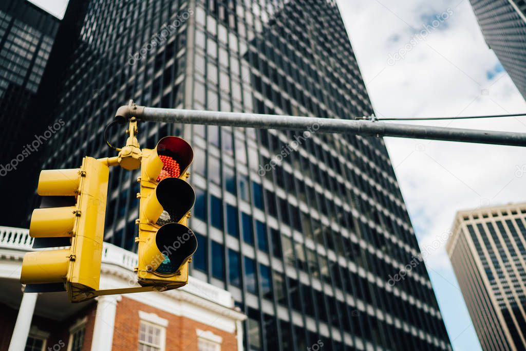 Equipment for controlling transport on ras hanging on urban background in modern business district of megalopolis, yellow traffic lights warning cars and pedestrians on intersection in downtow