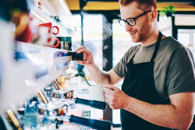 Optik gözlük beyaz erkek barista deneyimli kendi kafeteryasında emrindeki ayakta, bar ve hazırlama kahve içecek. Modern makine çalışma işlemi sırasında kullanarak kafe mutlu çalışanı
