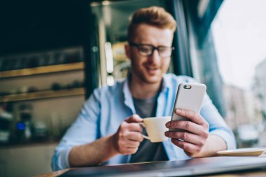 Seçici odak elini modern smartphone aygıtında. Süre tutarak telefon ve 4 g internet bağlantısı kullanarak izlerken video lezzetli kahve zevk olumlu hipster blogger