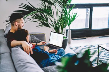 Sarılma genç karısı ve modern dizüstü cihaz üzerinde online bilet rezervasyonu kablosuz internet kullanımı ve ev konfor zevk kopyalama alanı alanı ile kocası. Daire içinde bilgisayar film izlerken evlilik