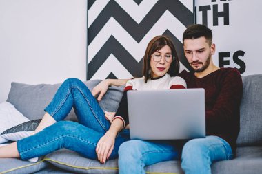 Çift birlikte modern dizüstü evde istirahat ile şık iç mekanlara kablosuz Internet bağlantısı kullanarak Web sitesinde alışveriş yaparken aşık. Genç evlilik netbook dairede online film izlerken