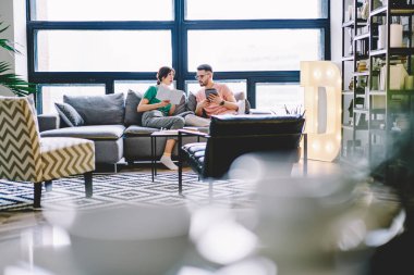 Dokunmatik yüzey birbirleriyle iletişim kurmak ve literatür bilgileri modern Flat rahat kanepede rahatlatıcı kitaptan tartışırken karısı ile boş zaman zaman geçirmekten ellerinde dalgın kocasıyla