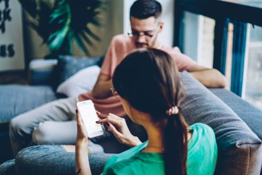 Arkadan görünüşü genç kadın online modern smartphone ev iç kanepede oturan internet siteniz için boş ekran ile sohbet. Sahte alanı ile dijital hücresel tarih seçici odak