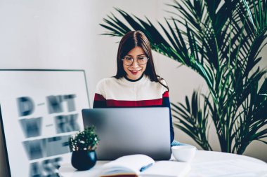 Kurs için internet sitelerinde olumlu hipster öğrenci arama bilgi iş modern dizüstü bilgisayarda kablosuz internet ile. Netbook evde oturan USB'yi neşeli genç kadın