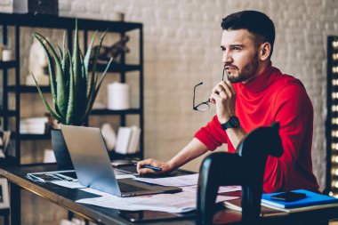 Genç adam serbest meslek modern dizüstü evde oturan gelişmekte olan iş başlangıç projesi için yaratıcı fikirler üzerinde düşünme düşünmek. Düşünceli hipster grafik tasarımcı netbook uzaktan çalışma