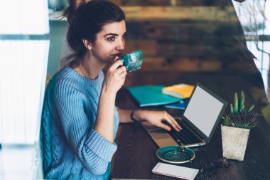 Kadın rüya profesyonel masaüstü mockup seyir perde uzakta kahve, sohbet online ve kapalı internet tarama için bilgisayar kullanan büyüleyici kadın yudumlarken ile dizüstü bilgisayar ile oturma