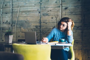 Kapalı modern laptop ve rahat kafeterya edebiyat, ciddi kadın vakit kullanarak otodidakt oturma masaüstünde bilgi sınavı için öğrenme netbook ile kadın öğrenci konsantre