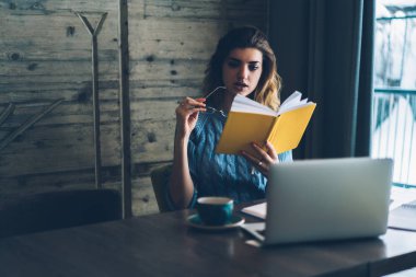 Düşünceli trendy hippi kız rahat kafeterya, yeni ilginç en çok satanlar, bilgi ve eğitim kavramı ile vakit dalgın kız öğrenci masada oturan edebiyat okuma