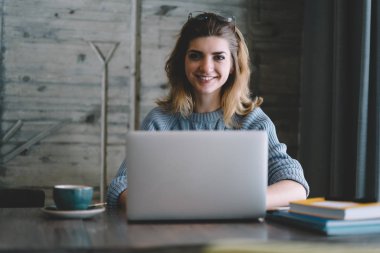 Genç yetenekli hippi kız kameraya e öğrenme ve otodidakt kapalı, zevk çatı iç kafeterya, modern dizüstü bilgisayar ile zaman geçirmekten mutlu gülümseyen kadın portresi