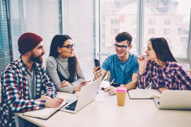 Başarılı gülümseyen hipster adam smartphone ile alanı, Grup teknolojisi kapalı ile zaman geçirmekten mutlu öğrenci coworking, arkadaşlarıyla otururken 4 g bağlantı üzerinden görüntülü arama yapma