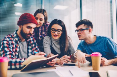 Kadın ve erkek öğrenciler ortak projesinde modern sınıf oda, Genç kadın ve erkek deskto at Sınav Hazırlık Kampüsü zaman harcama eğitim hakkında konuşmak yaparken ev ödevi üzerinde işbirliği