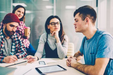 Analiz ve girintili coworking, başlangıç projesi tartışmaya bin yıllık erkek ve kadın Öğrenciler kampüs, üniversite arkadaşlarıyla ev ödevi teamworking görev açıklayan genç yakışıklı hipster adam