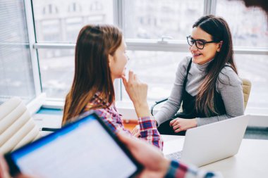 Teknoloji ve iletişim, ara a dizüstü bilgisayar modern coworking uzayda hipster kızlar görüşmeler yoluyla öğrenme e arkadaşıyla konuşurken gözlük başarılı neşeli kız öğrenci kavramı