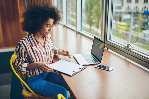 物思いにふけるアフリカ系アメリカ人の学生の情報を確認し ワイヤレス インター ネットに接続されているコンピューターに座って宿題をやってします 熟練した黒い皮のコワーキングのコースの仕事で働く若い女性 — ストック写真