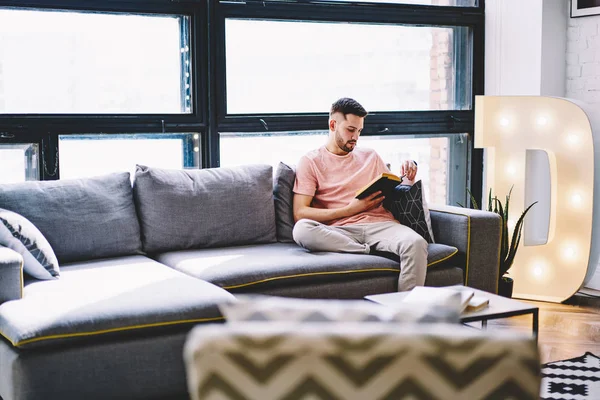 Hombre Joven Pensativo Descansando Casa Sofá Cómodo Libro Lectura Apartamento —  Fotos de Stock