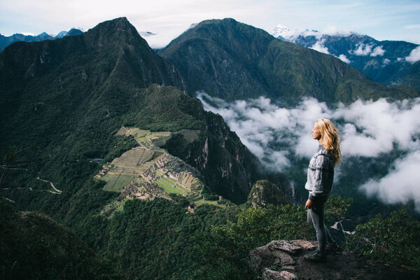 Young woman tourist enjoying amazing scenery of mountains ranges during trekking trip on holidays.Female traveler admiring beautiful view from high peak during exploring natural environment