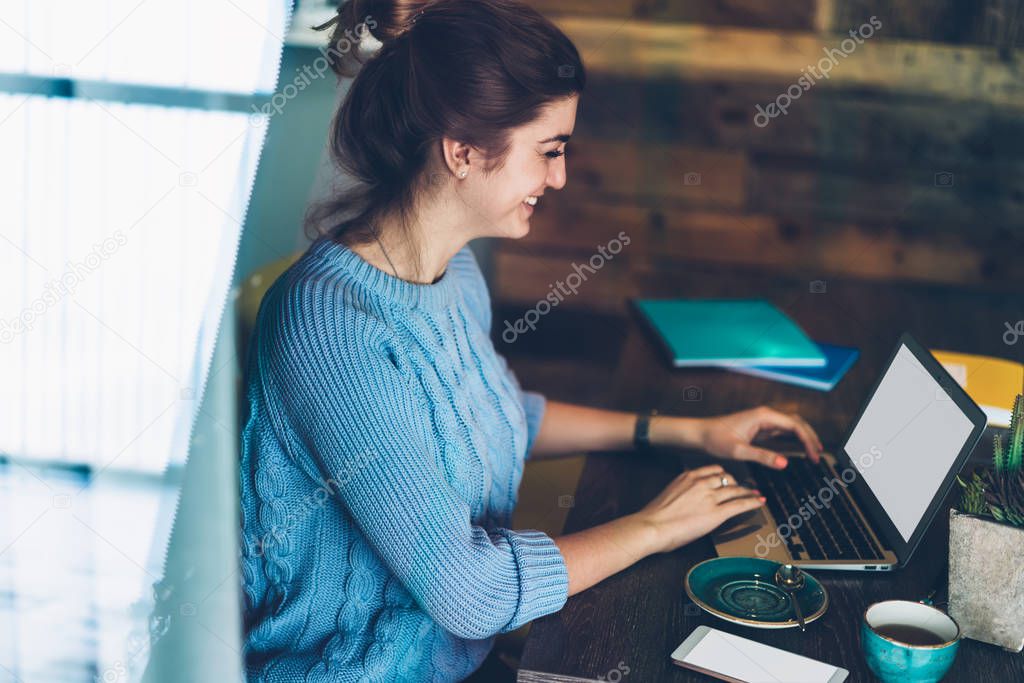 Smiling female software developer creating website feeling excited from good work on laptop computer, happy hipster girl searching information and chatting with followers via netbook at campus