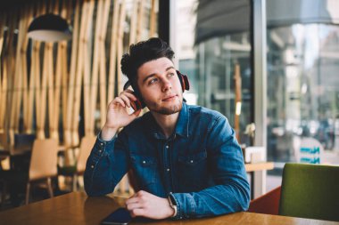 Rüya gibi genç adam cep ve kulaklık ile müzik keyfi ile bluetooth, café iç elektronik aksesuarlar ve telefon üzerinden sesli kitap için oturup yakışıklı hipster adam bağlı