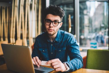 Gözlük arıyorum kamera oturma dizüstü bilgisayar holding kredi kartı yakınındaki, adam hipster giriş ve online qaimənin netbook için yapma para, vizyon koruma için genç adam portresi
