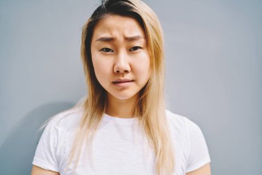 Kameraya bakarak poz çekici ciddi ve üzücü Asyalı kadın kişinin portre. Güzel Çin uyruklu kadın açık doğal cilt arıyorsunuz ile endişeli. Hiç makyaj yüz görünümünü kapat