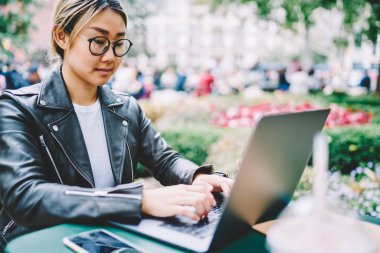 Online bilet rezervasyonu ve parkta oturan sırasında netbook üzerinde popüler web sitesinde online hizmet ile ödeme yapma daha iyi görüş için bardaklarda çekici konsantre kadın Blogger resim kırpılmış