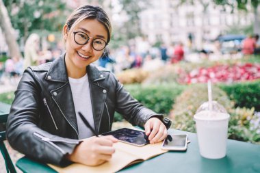 Açık havada otururken bilgileri kaydetme göz koruması için gözlük güzel müreffeh kadın yazarın yarım uzunluk portre. Street serbest zaman harcama şirin neşeli Asya hippi kız