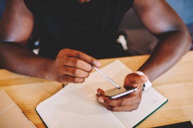 Afro-Amerikan adamın dijital gadget ve online rezervasyon, üstten görünüm koyu tenli adam akıllı telefon ve elektronik kalem uygulama bankacılık faturaları imza kullanarak yapmak için ekran kalemi tutan resim kırpılmış