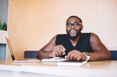 Online ders, koyu tenli adam serbest meslek Office uzak iş sırasında kameraya bakarak gülen dizüstü bilgisayar kullanan kitaplığında öğrenme neşeli Afrikalı-Amerikalı adam portresi memnun